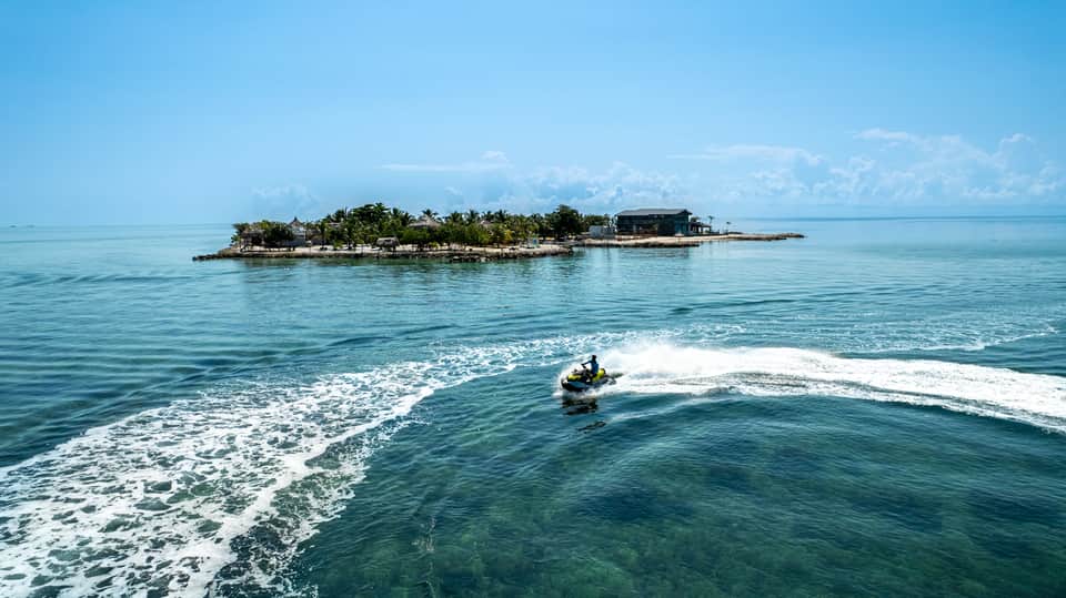 Tropical island resort with turquoise ocean waves and jet ski activity