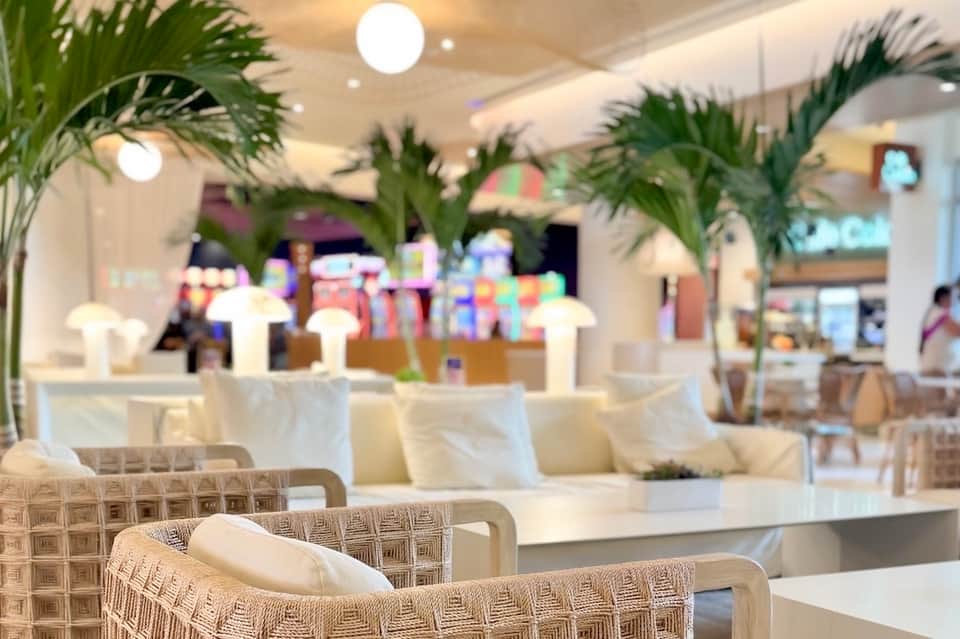 Upscale restaurant dining area with palm plants, white napkins, ambient lighting, and modern furnishings
