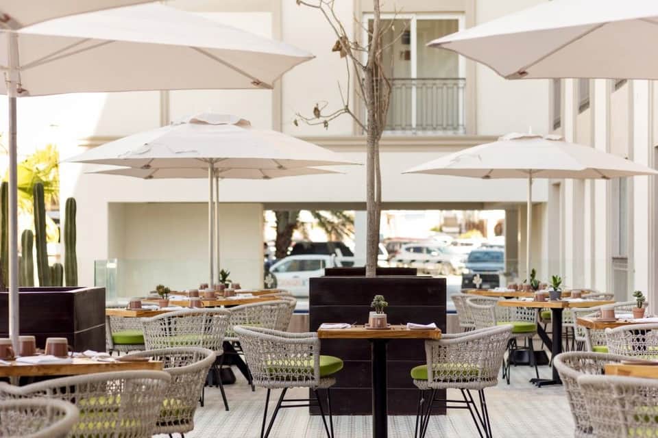 Outdoor dining patio with woven chairs, umbrellas, and modern architecture