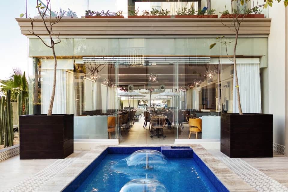 Modern resort dining area with floor-to-ceiling glass doors overlooking reflecting pool