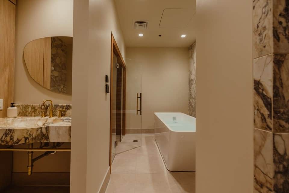 Luxury bathroom with marble accents, freestanding white soaking tub, walk-in shower, and double vanity