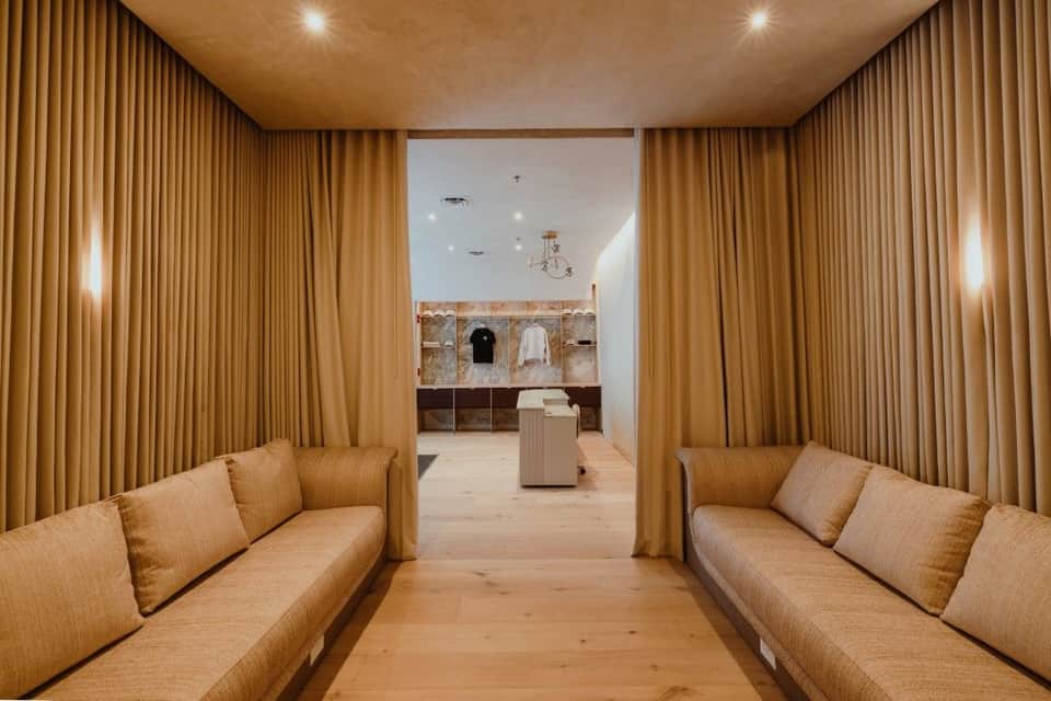 Spa relaxation lounge with tan velvet sofas, gold curtains, and contemporary stone shelving