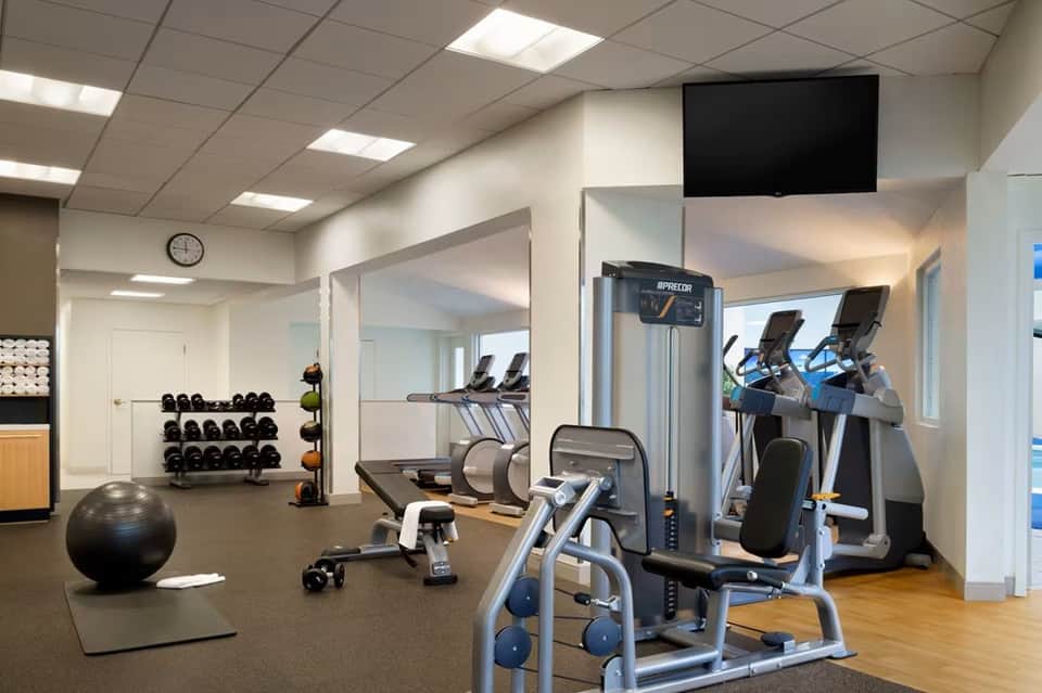 Hotel fitness center with treadmills, weights, exercise equipment, and mirrors