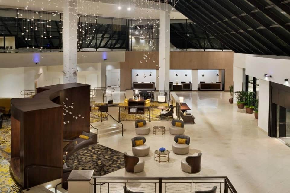 Modern hotel lobby with high ceilings, hanging light installation, and seating areas
