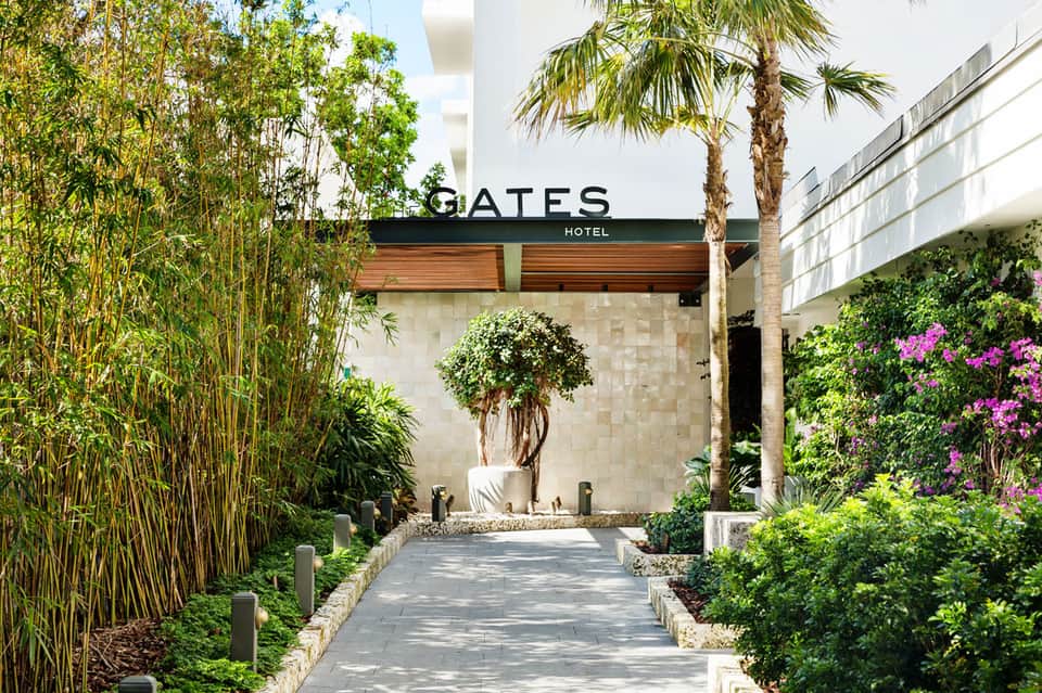 Gates Hotel entrance with modern architecture, manicured gardens, bamboo plants, and palm trees