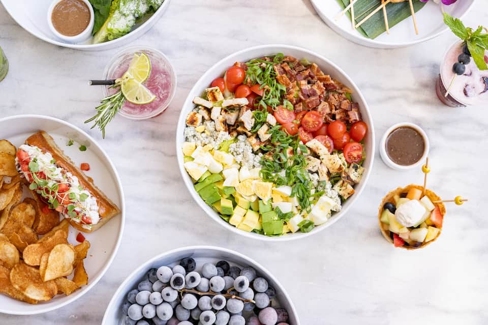 Overhead view of colorful salad bowls, sandwiches, and refreshing beverages