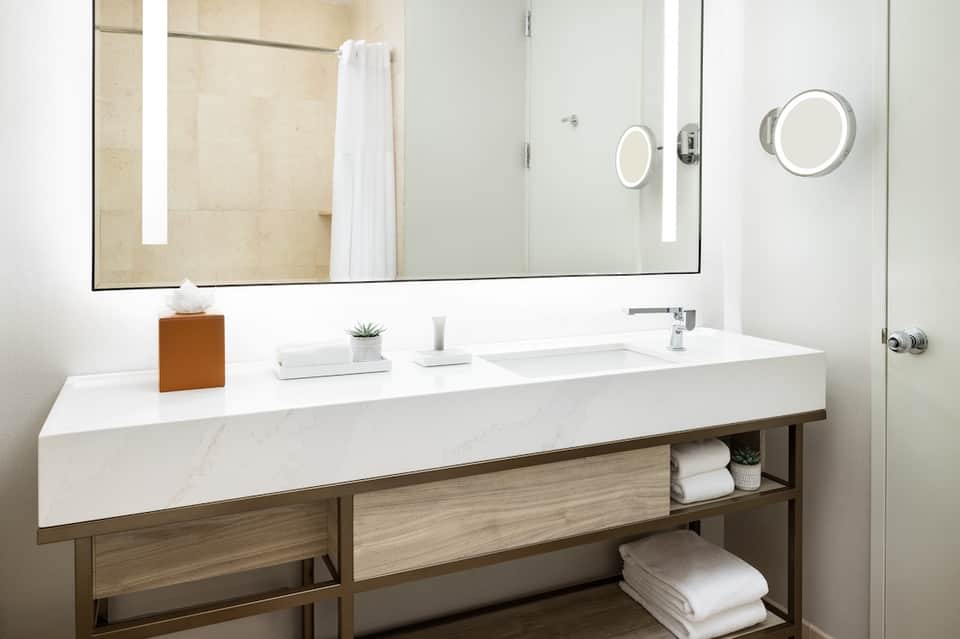 Modern hotel bathroom with white marble vanity and illuminated mirror