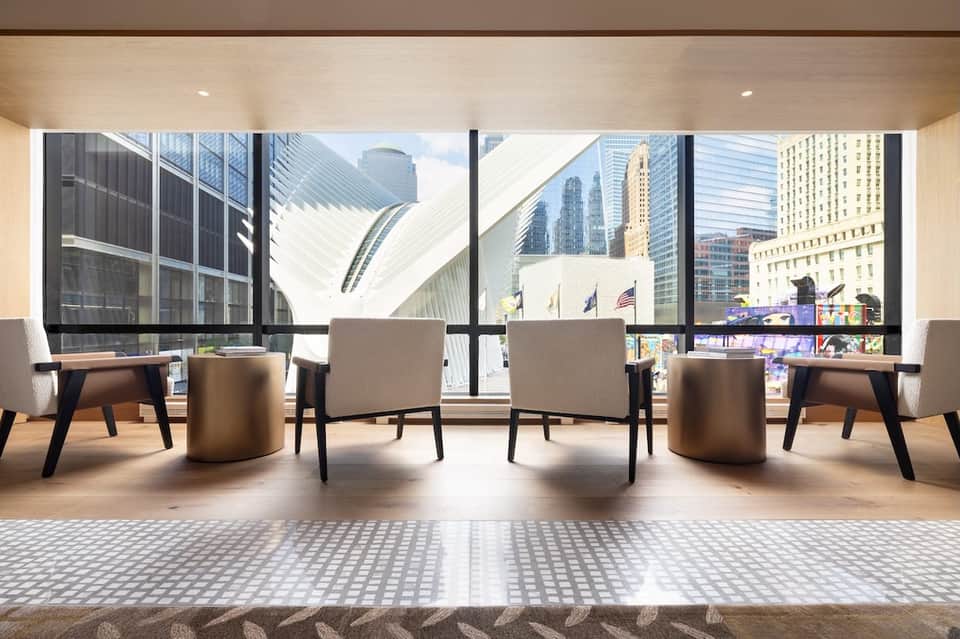 Modern lounge with floor-to-ceiling windows overlooking city skyline and architectural landmarks
