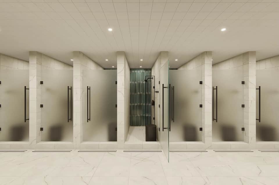 Contemporary fitness center with multiple shower stalls featuring frosted glass enclosures and marble flooring