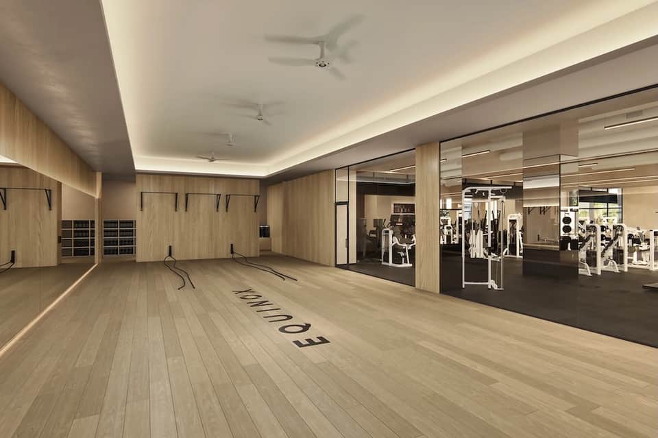 Modern gym with wood finishes, large mirrors, cardio equipment, and separate fitness machines area with glass partition