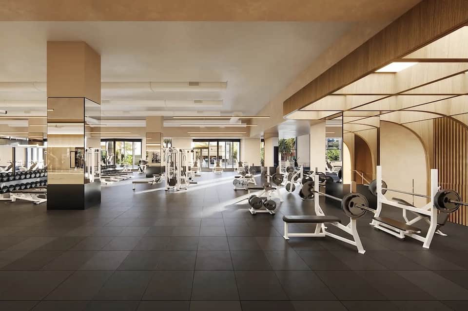 Spacious modern fitness center with cardio equipment, weights, and bright natural lighting throughout