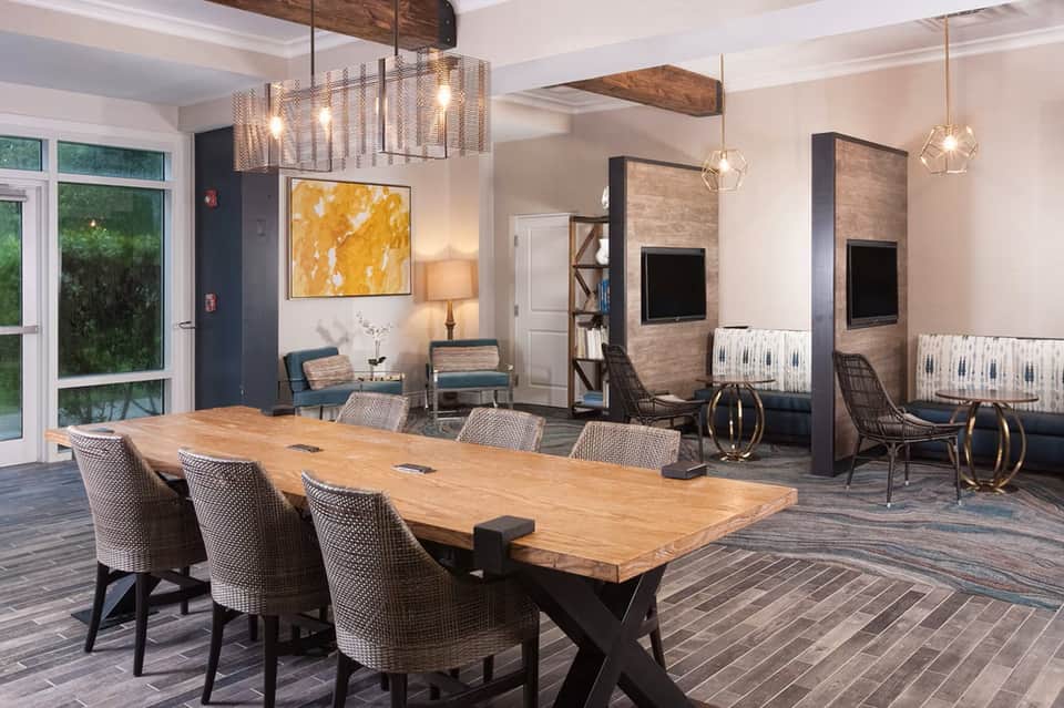 Hotel meeting room with wooden dining table, upholstered chairs, and modern fireplace installations