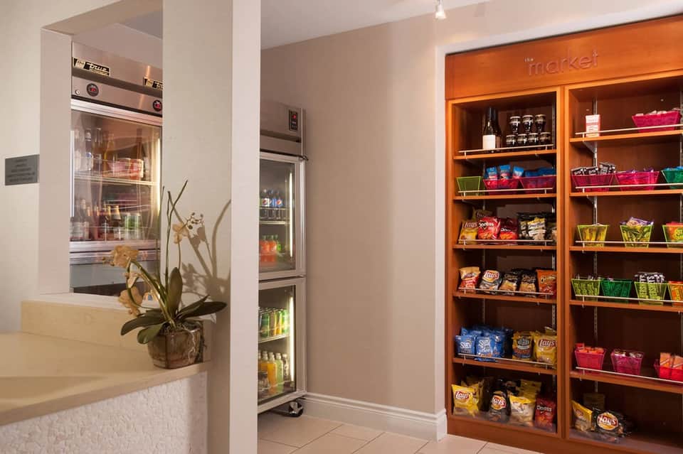 Hotel market and snack area with refrigerated beverage display and wooden shelving with snacks