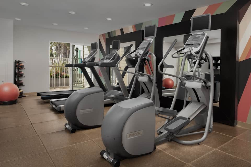 Fitness center with cardio equipment, exercise bikes, and red accent wall design elements