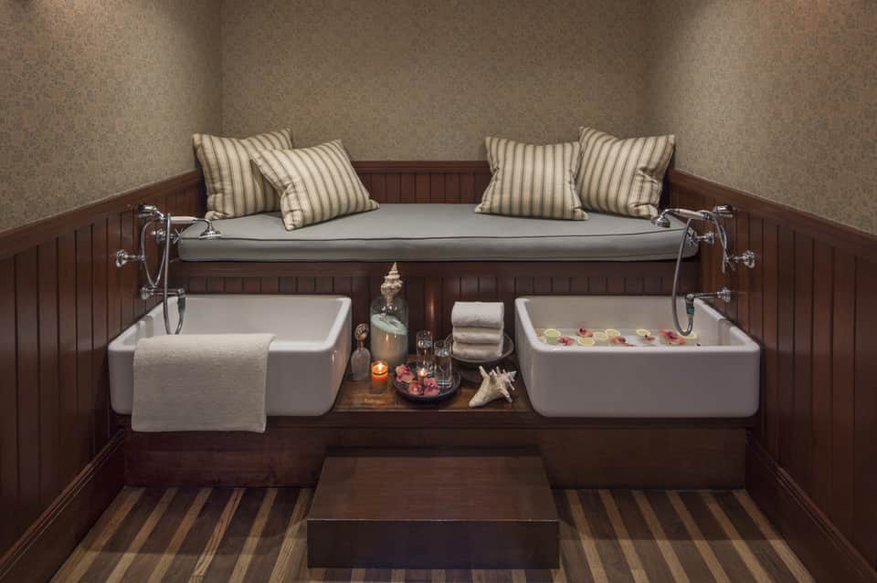 Spa relaxation room with dual soaking tubs, striped pillows, candles, and wood accents