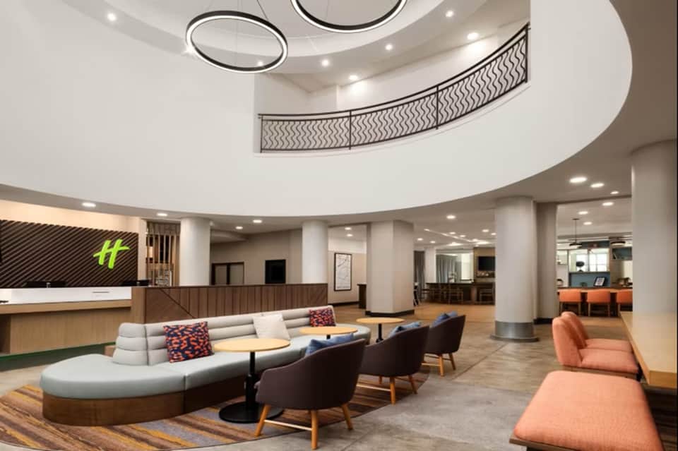 Modern hotel lobby with curved seating, circular ceiling lights, reception desk, and contemporary furniture