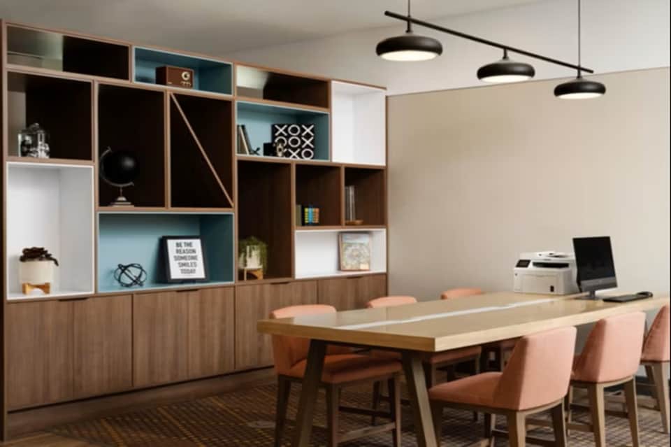 Modern office space with wooden and white modular shelving, conference table, pink chairs, and pendant lighting