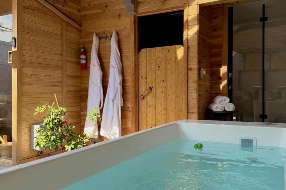 Outdoor hot tub with wooden walls, white towels, and modern minimalist design in spa setting