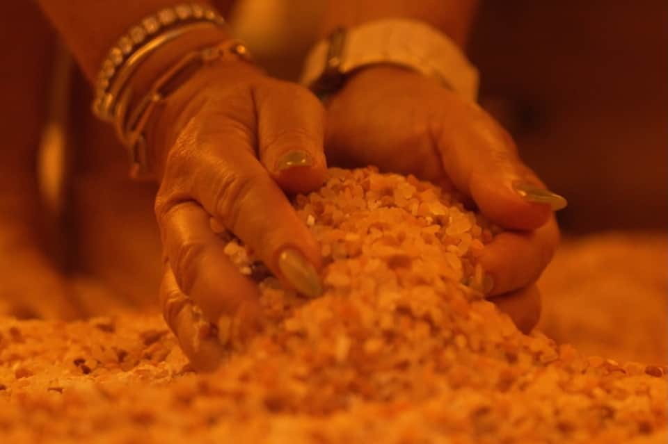 Hands applying turmeric paste or spice during wellness or beauty treatment ritual
