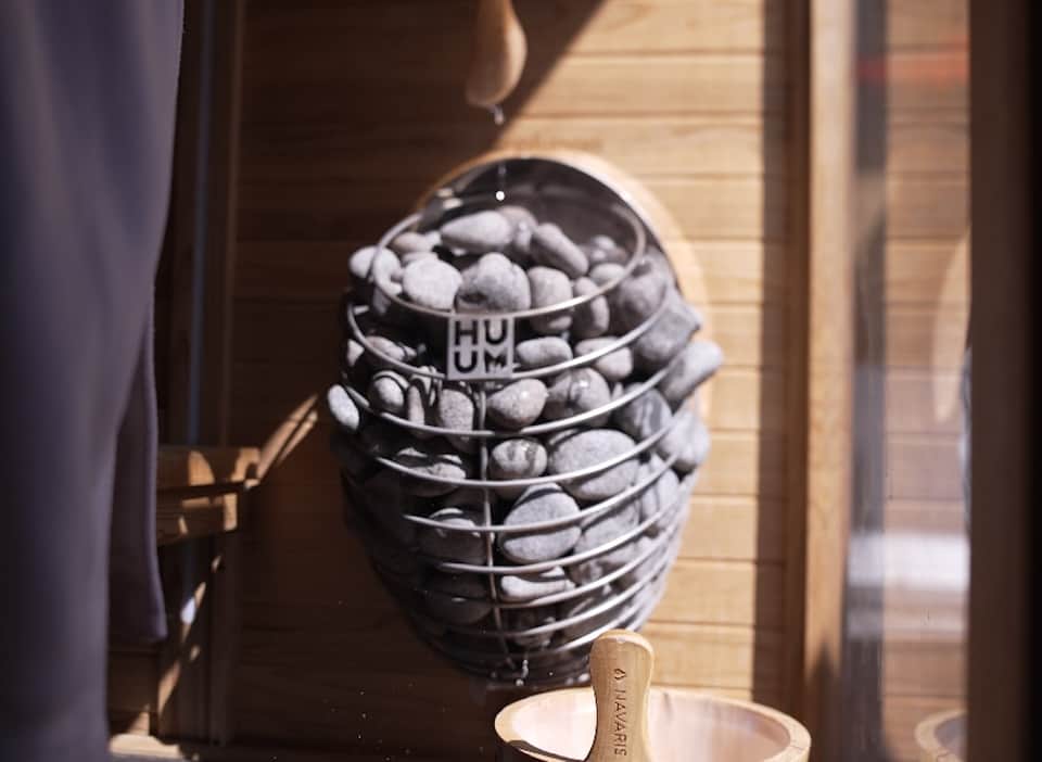 Basket of artisanal bread rolls labeled with hotel branding on wooden surface