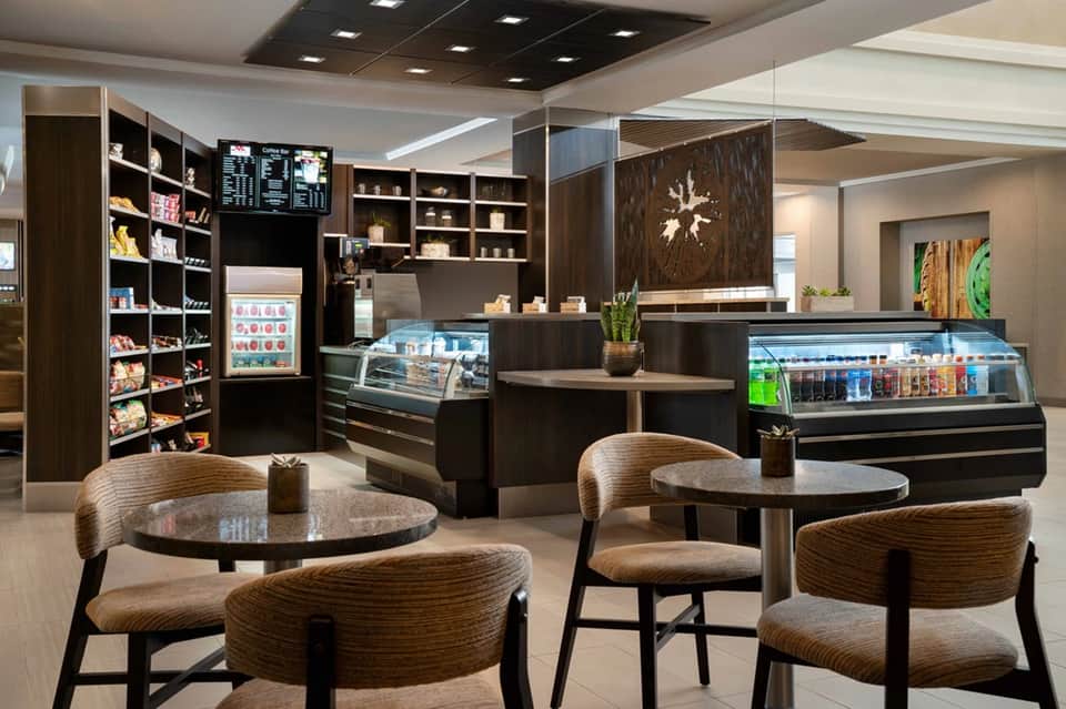 Modern café interior with dark wood cabinetry, display cases, seating area, and contemporary furnishings