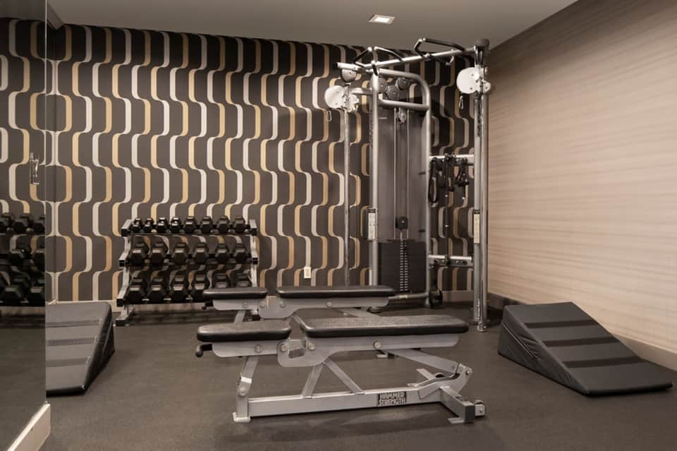 Modern resort fitness center with geometric patterned walls and strength training equipment