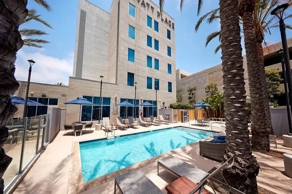 Urban hotel courtyard with heated swimming pool, blue umbrellas, and multi-story building facade