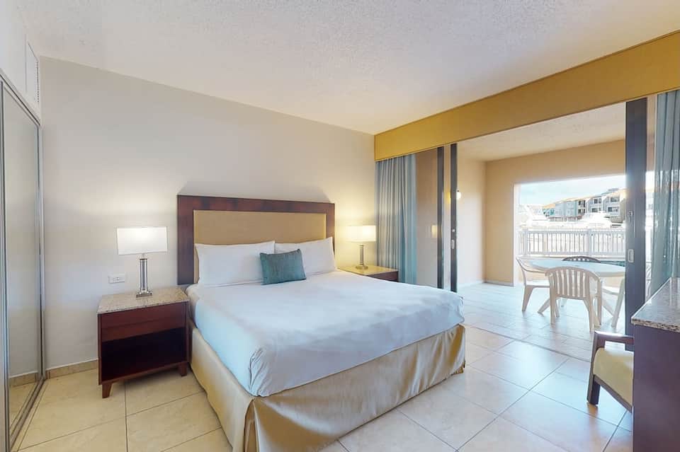 Modern hotel bedroom with queen bed, balcony access, and contemporary furnishings