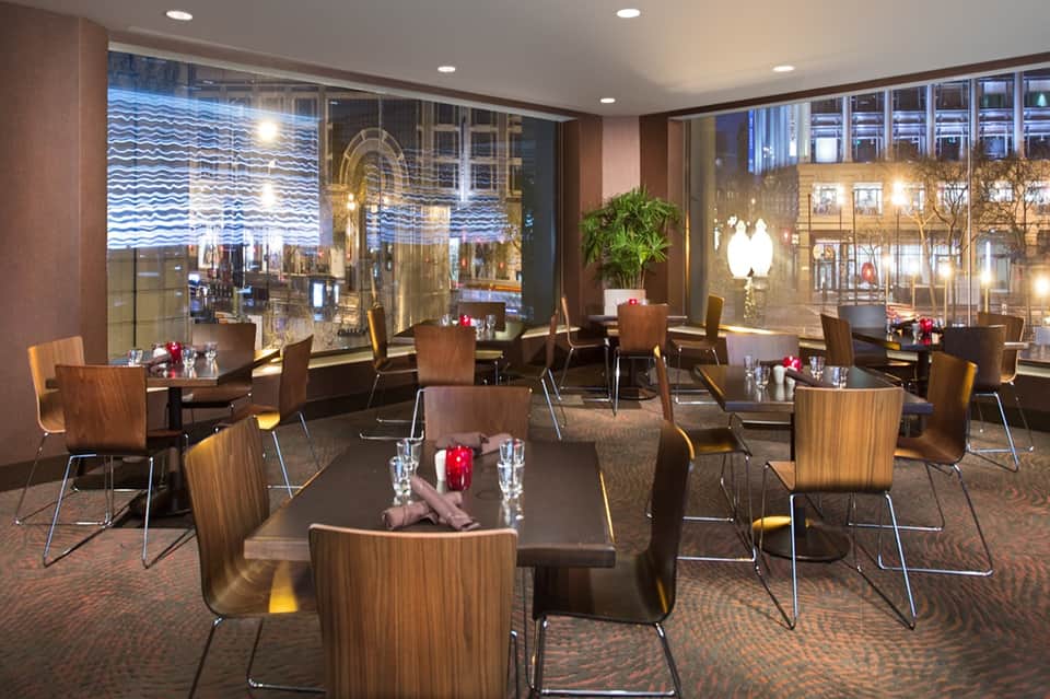 Upscale lounge with city views, wooden chairs, ambient lighting, and contemporary furnishings