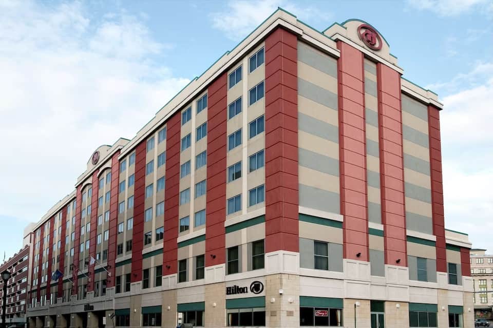 Hilton hotel multi-story building with red and beige striped facade, white trim, and ground-level retail space