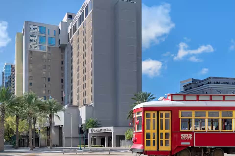 Hotel tower on downtown street with historic red cable car and palm trees in urban setting
