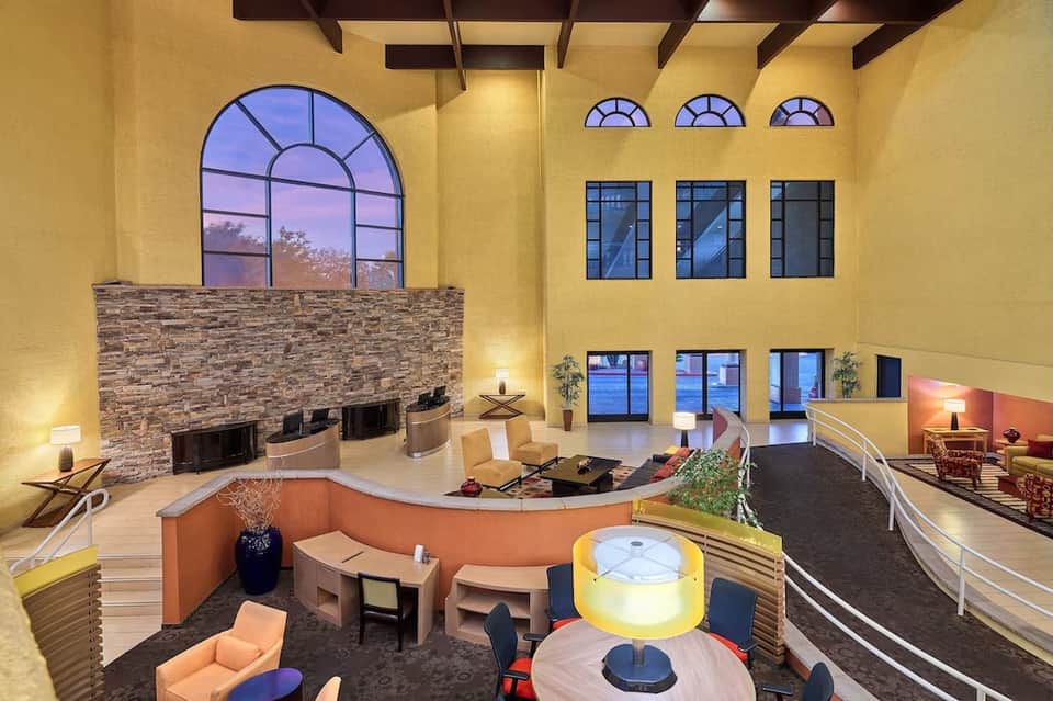 Grand multi-level atrium lobby with dramatic yellow walls, stone fireplace, and contemporary seating areas