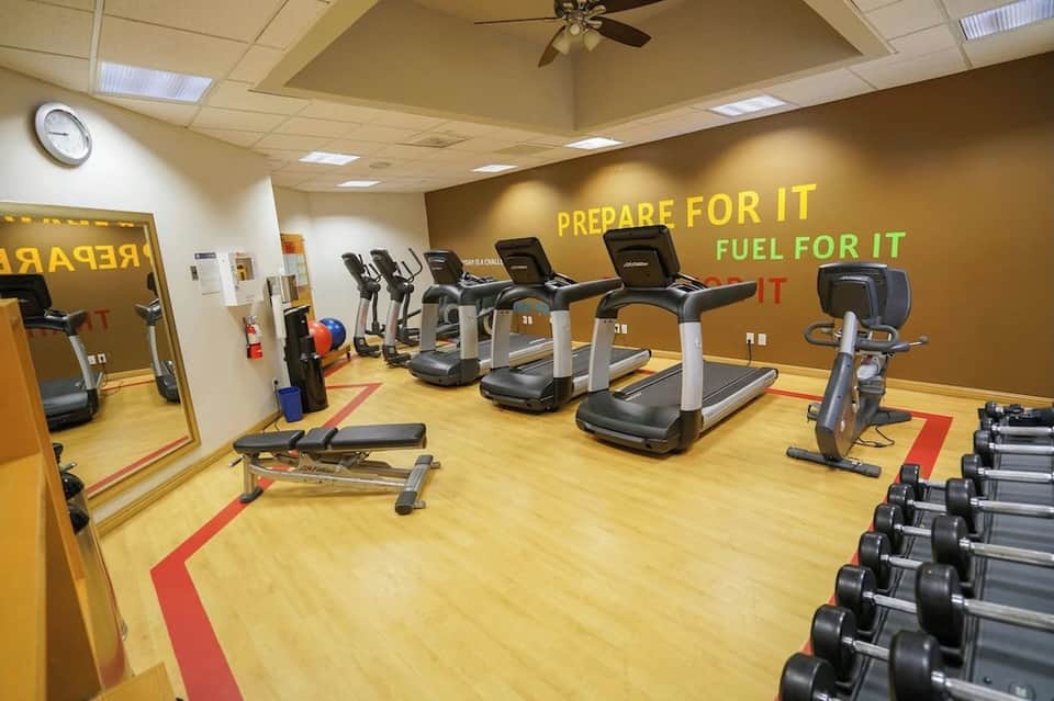 Bright fitness studio with treadmills, exercise bike, and motivational wall text