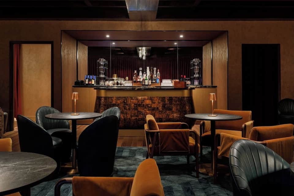 Upscale bar lounge with bronze and amber tones, leather seating, decorative bar with glass shelving