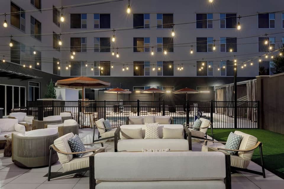 Evening courtyard lounge with firepit, seating, umbrellas, and string lights