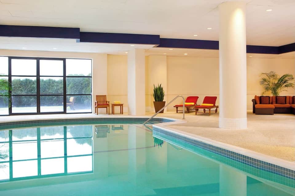 Indoor swimming pool with large windows, lounge seating area, and modern architecture