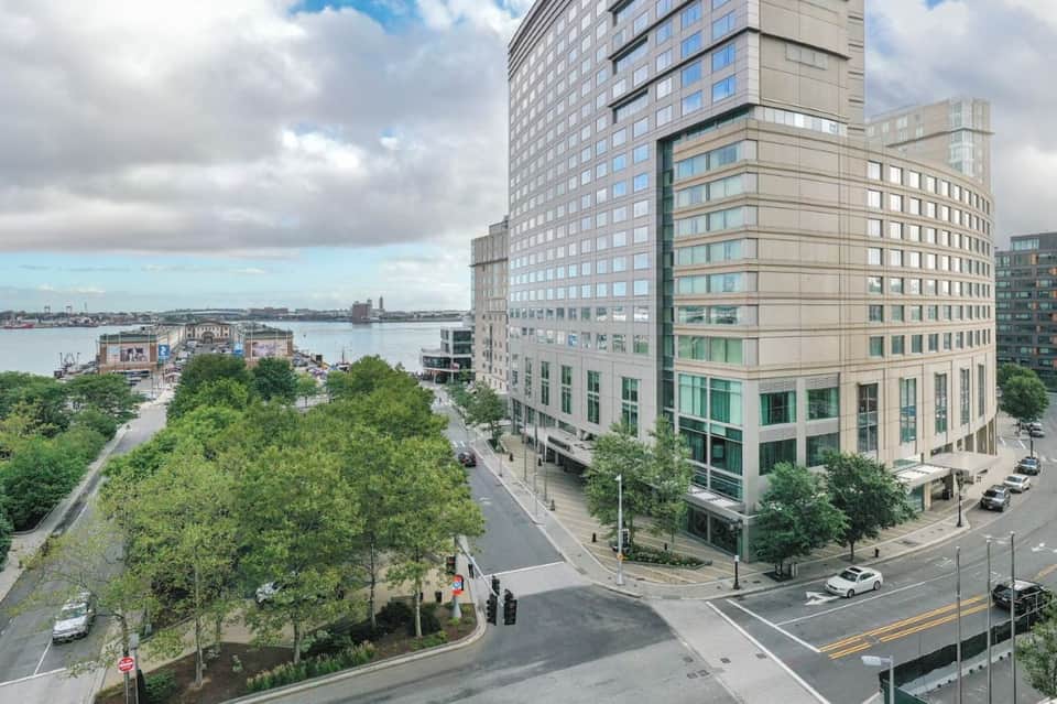High-rise hotel building overlooking waterfront park and river with urban cityscape
