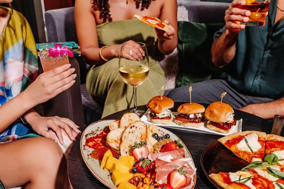 Social gathering with guests enjoying cocktails, pizza, and appetizers indoors