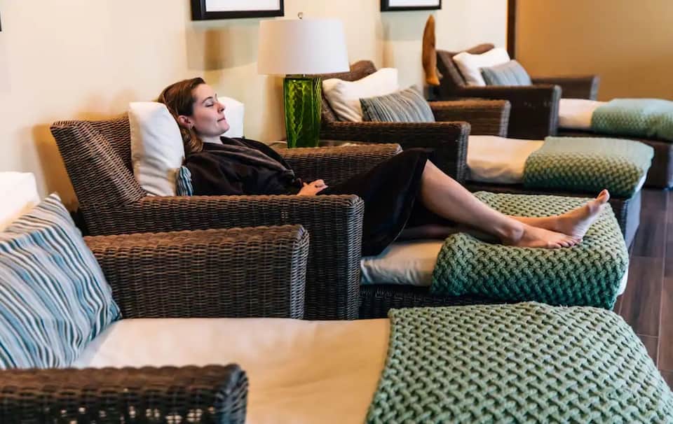 Relaxation lounge with woman in wicker chair and green patterned ottoman seating