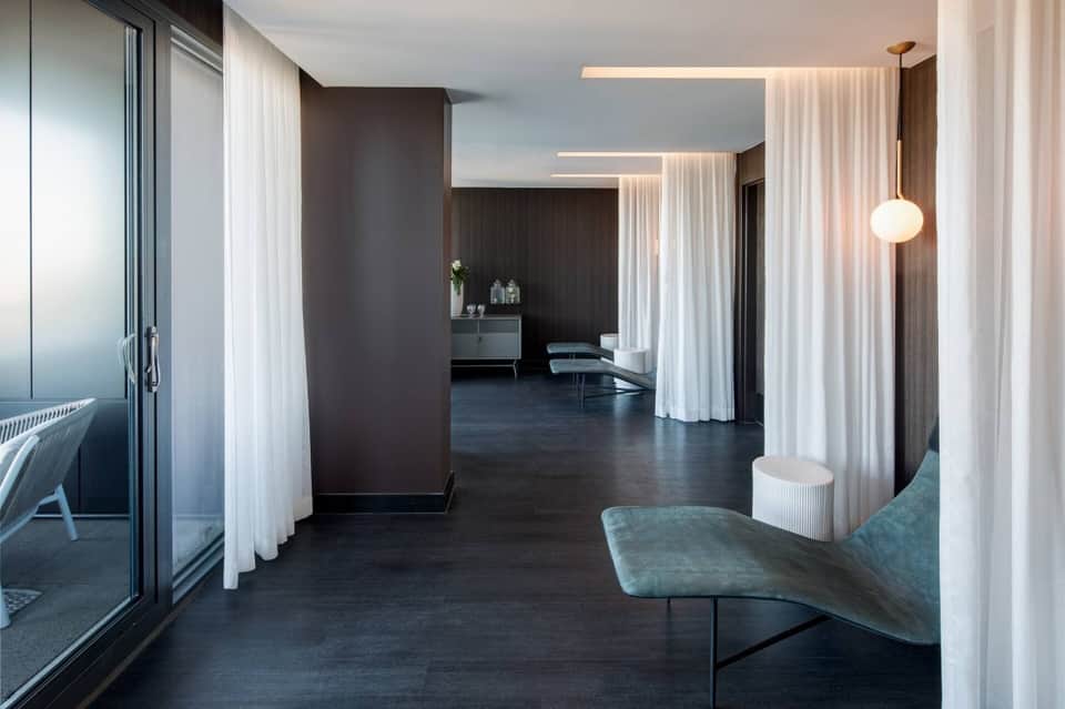 Minimalist spa corridor with white flowing curtains, dark flooring, and contemporary pendant lighting