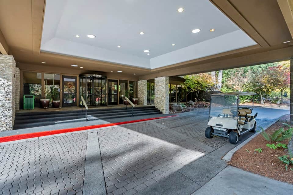 Modern hotel entrance with stone pillars, glass doors, and red carpet entrance walkway