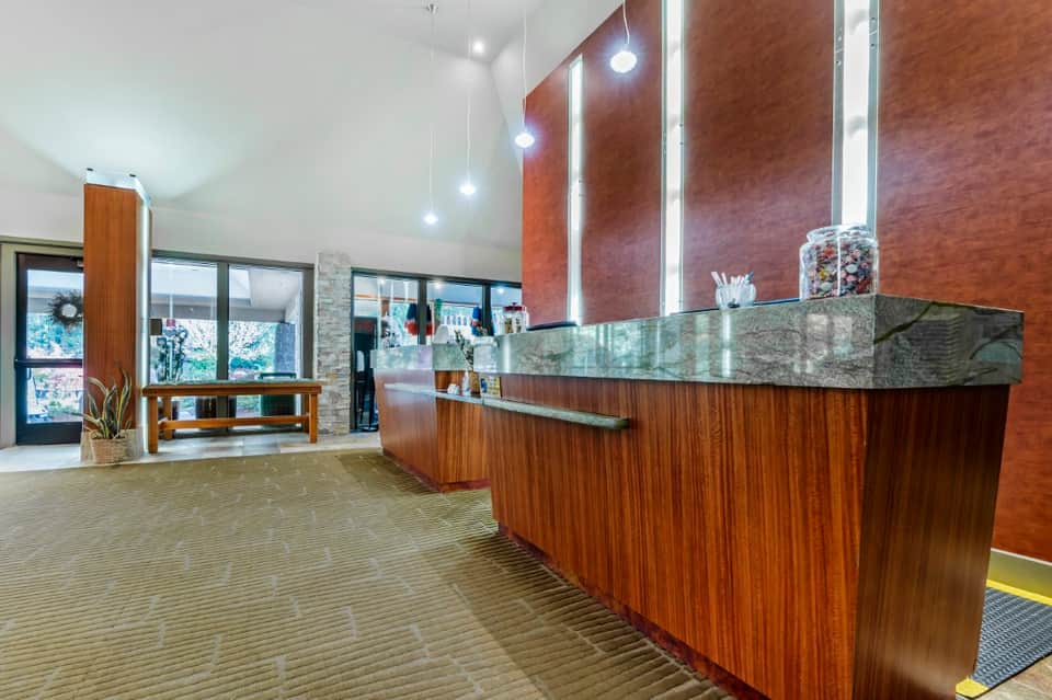 Modern hotel lobby with wood-paneled reception desk, geometric mirrors, and stone accent wall