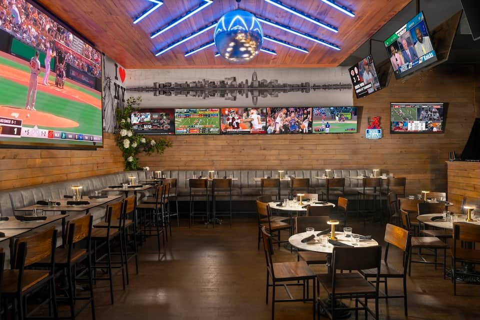 Sports bar interior with wooden ceiling, multiple screens showing games, and bar seating