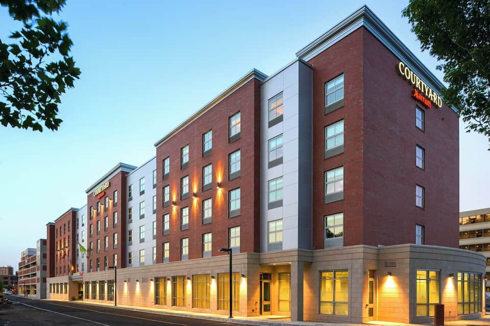 Courtyard by Marriott hotel exterior at dusk with brick and stone facade, illuminated ground level