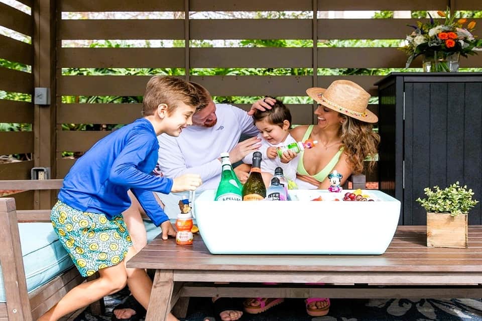 Family enjoying beverages on outdoor terrace with wooden bench seating and slatted privacy screen