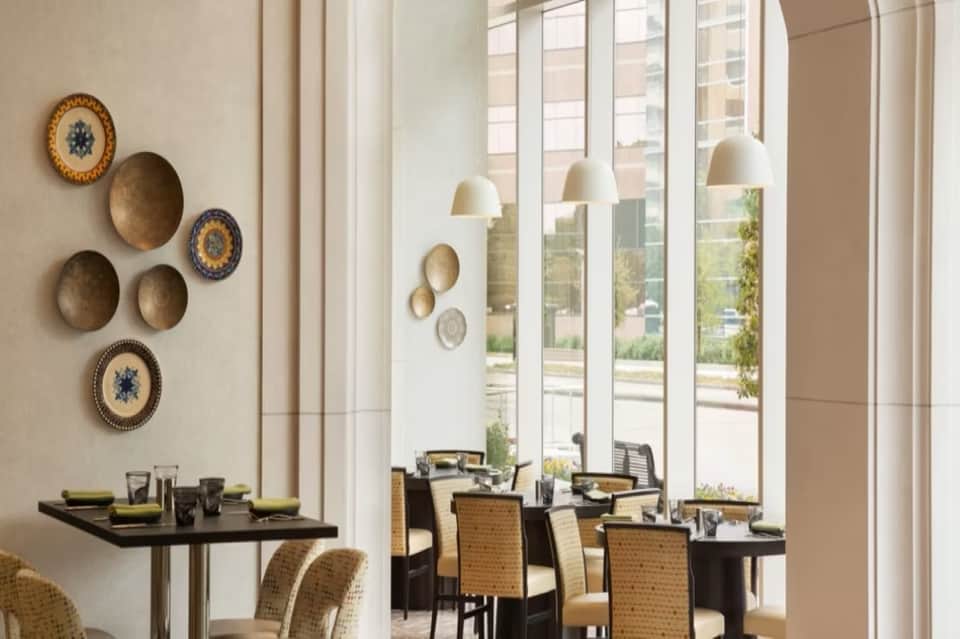 Hotel dining room with floor-to-ceiling windows, pendant lighting, and wall plate decor