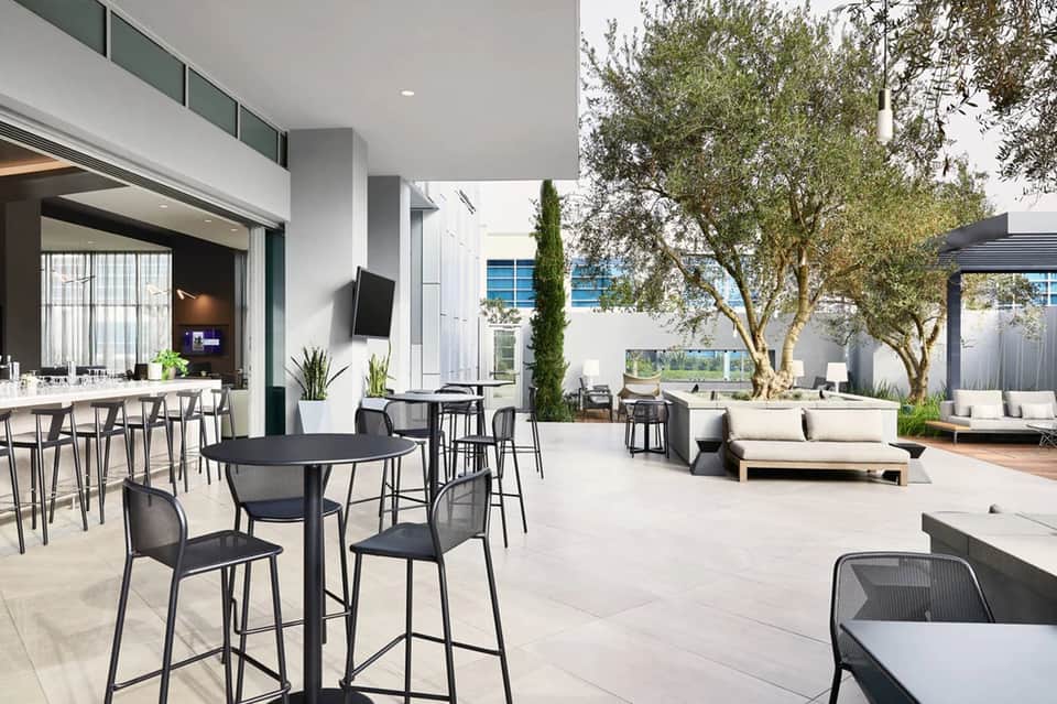Modern resort courtyard with outdoor bar, seating areas, and Mediterranean landscaping