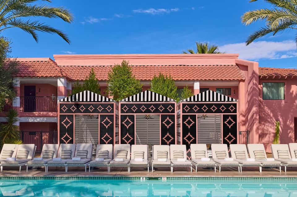 Resort pool area with terracotta buildings, ornate dark gates, and white lounge chairs