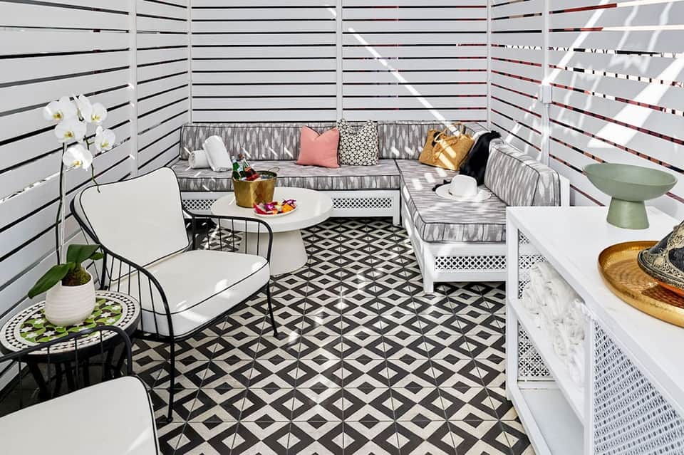 Modern rooftop lounge with white privacy screens, gray seating, geometric black and white floor tiles