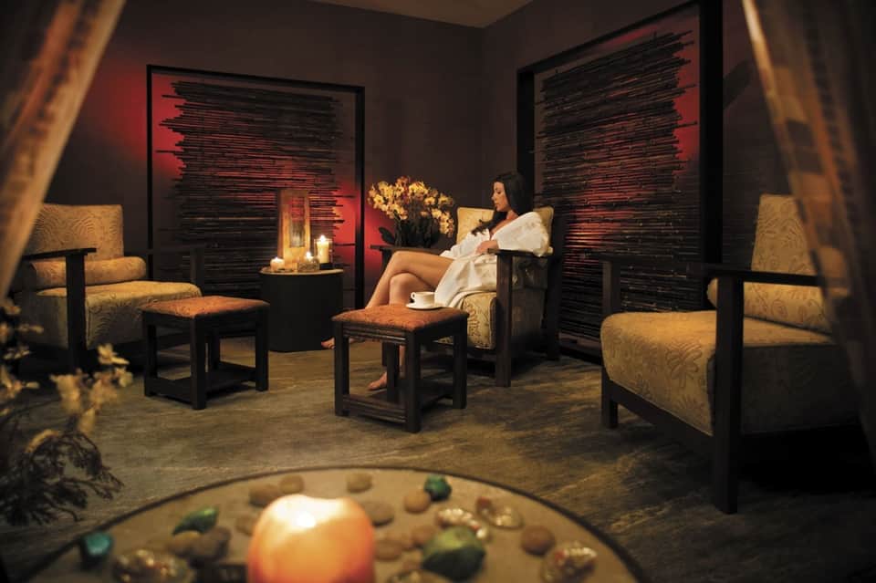 Spa relaxation room with dim lighting, gold accents, and comfortable seating
